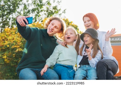 Portraits Of Three Smiling Sisters And Brother Teen Taking Selfie Portrait Using A Modern Smartphone Camera. Careless Happy Young Teenhood, Childhood Time And Modern Technology Concept Image.