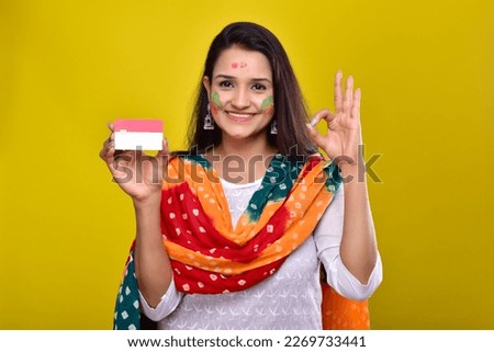 portraits of young woman celebrating holi and showing credit card