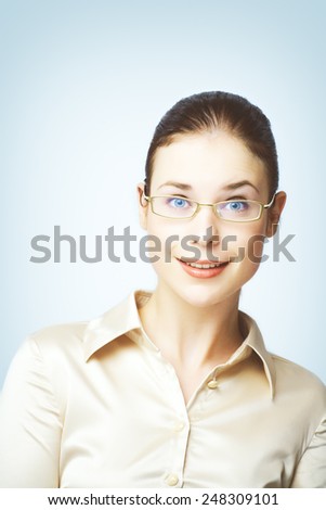 Portraits of young woman wearing glasses and silk blouse photographed on blue background. 