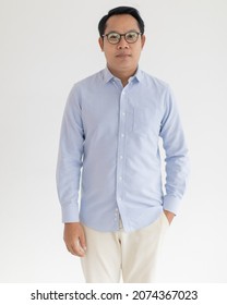 Portrat Close Up Studio Shot Of Asian Happy Middle Aged Chubby Plump Male Model Wearing Optical Eyeglassess With Blue Casual Shirt Standing Smiling Look At Camera In Front Or White Wall Background.