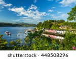 Portree skyline with colorful houses at the harbor with boats in bay, blue sky and trees in the foreground