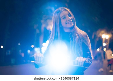 Portreit Of Young Girl On Electric Scooter At Night Blurry