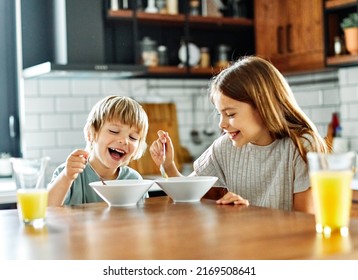 Portret of brother and sister having fun together eating breakfast in kitchen