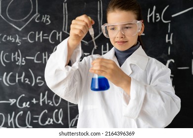 Portret of serious girl in white uniforms conducting chemical experiments in a laboratory. Young scientists. Natural sciences. school education of children. Back to school concept.