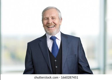 Portriat of old businessman is laughing hard. Caucasian senior businessman laughing out loud. Bright window background.