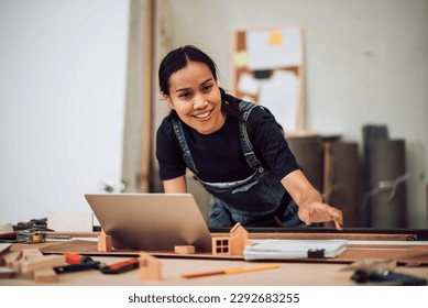 Portriat of small business owner adult asian female carpenter working a wood work in carpentry workshop. Entrepreneur woman handcrafting and design minimal home furniture. - Powered by Shutterstock