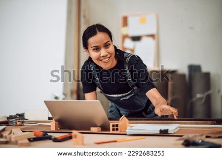 Portriat of small business owner adult asian female carpenter working a wood work in carpentry workshop. Entrepreneur woman handcrafting and design minimal home furniture.