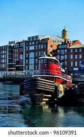 Portsmouth, New Hampshire skyline with tugboat in foreground.