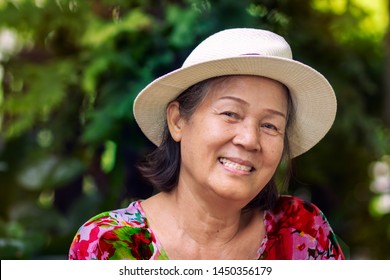 Porttrait Image Of 60s Or 70s Asian Elderly Woman In Colorful Outfit With Hat.Beautiful Old Lady Smiling In The Park.Concept Of Happy Healthy Retired Senior People. 