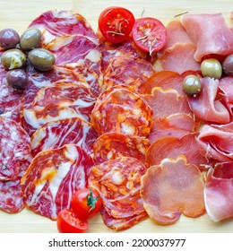 Portuguese Charcuterie Board, With Slices Of Cured Pork Meats, Olives And Cherry Tomatoes. Cured Ham, Chorizo, Smoked Pork Loin And More. Wood Background.