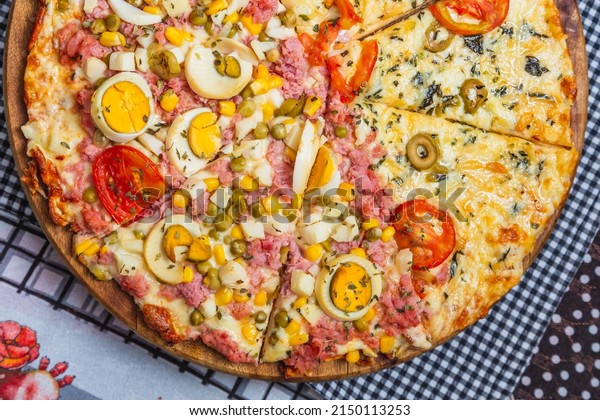 Portuguese pizza and margarita\
pizza together in one pizza. sliced ​​and divided, baked\
pizza,