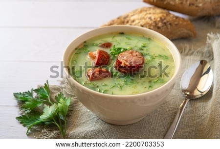 Portuguese style soup called Caldo Verde with traditional bread on white wooden Table. Copy space