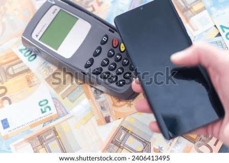 Pos payment terminal and Euro banknotes of different denominations on background.