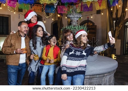 Posada Mexican family taking photo selfie with mobile phone and Singing carols in Christmas party in Mexico Latin people