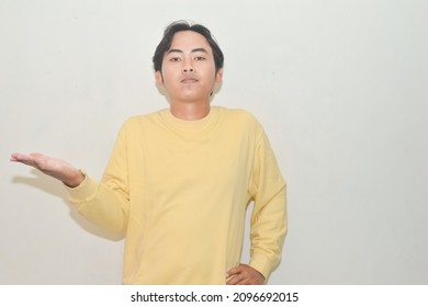 Pose Of Asian Man Shrugging Both Shoulders And Raising Both Hands. Illustrations Of Ignorance, Why Not, Where, And What's Wrong. Portrait Of Indonesian Man On Isolated White Background