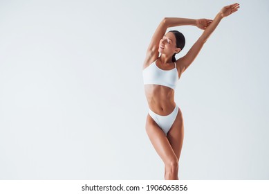 Posing for a camera. Beautiful woman with slim body in underwear is in the studio.