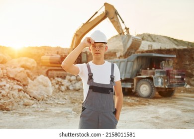 Posing for a camera. Worker in professional uniform is on the borrow pit at daytime.