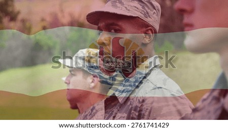Posing central soldier looking left on grass, wearing camo uniform and patrol cap, flag overlay. Military, formation, camaraderie, discipline, emblem, banner, insignia