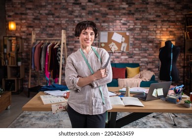 Posing in front of the camera charismatic and attractive dressmaker woman at her modern tailoring atelier she holding the tailoring scissors and smiling cute - Powered by Shutterstock