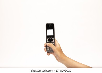 posing photograph of a female hand holding a black cordless phone and typing a phone number on a white background - Shutterstock ID 1748299010