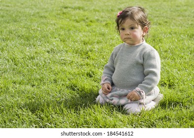 Posing Serious Baby Girl Sit On Grass Alone