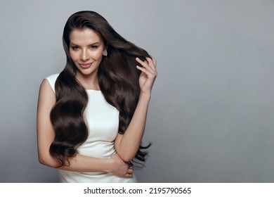 Posing woman brunette. Young smiling woman with perfect hairstyle wearing gold earring on white banner background