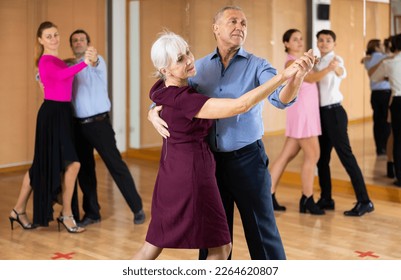 Positive active elderly couple enjoying slow foxtrot in dance studio. Amateur social dancing concept - Powered by Shutterstock