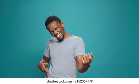 Positive Adult Doing Air Guitar Performance In Front Of Camera, Playing Modern Instrument To Have Fun In Studio. Carefree Happy Man Having Musical Skills, Singing And Dancing For Leisure Activity.