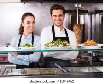 Positive Adult Restaurant Staff Posing At Kebab Counter And Smiling