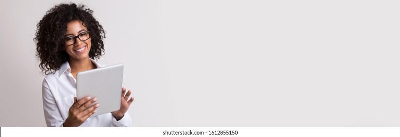 Positive african american business lady using digital tablet, light panorama background, empty space