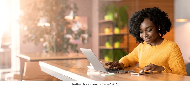 Positive african american businesswoman using mobile phone, working with laptop in cafe, copy space - Powered by Shutterstock