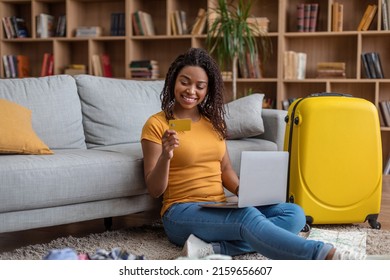 Positive african american lady using credit card and laptop pc, surfing online travel agency website, booking abroad trip or making hotel reservation on web, sitting on floor at home - Powered by Shutterstock