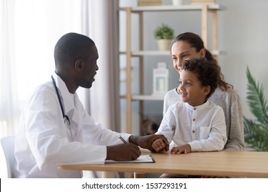 Positive african American male pediatrician talk with little boy patient, smiling young mother and small toddler son visit doctor, do annual checkup in clinic or hospital, children healthcare concept - Powered by Shutterstock