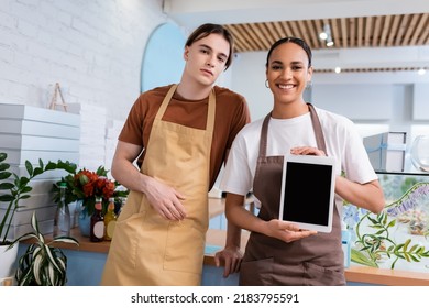 Positive african american seller showing digital tablet near colleague in sweet shop - Powered by Shutterstock