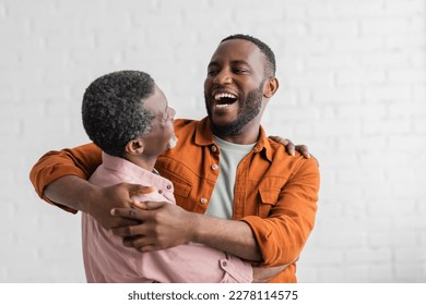 Positive african american son hugging mature father in living room - Powered by Shutterstock
