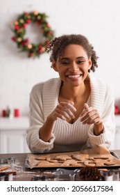 Positive African American Woman Looking At Camera Near Christmas Cookies In Kitchen