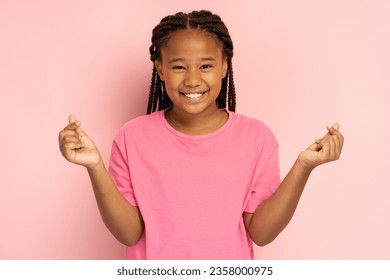 Positive African girl in pink t shirt gesturing showing heart from fingers, k pop culture, isolated on pink background, mockup. Young modern child with toothy smile looking at camera - Powered by Shutterstock