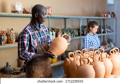 Positive African Potter Enjoying Work, Checking Ceramic Products In Pottery Studio