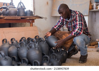 Positive African Potter Enjoying Work, Checking Ceramic Products In Pottery Studio