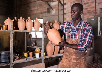 Positive African Potter Enjoying Work, Checking Ceramic Products In Pottery Studio