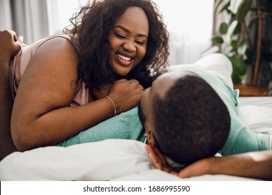 Positive Afro American lady leaning to her beloved man in bed