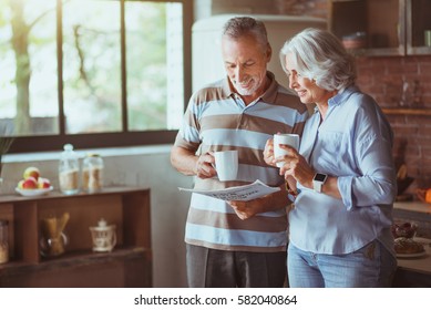 Positive aged loving couple reading newspaper - Powered by Shutterstock