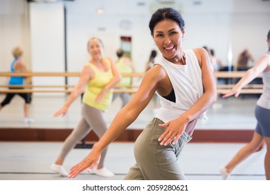 Positive asiatische Frau, die in einer weiblichen Gruppe tanzt, praktiziert energisches Schauen in einem Tanzstudio