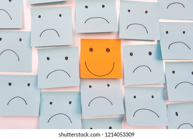 Positive Attitude and Happy Concept. Hand Drawn A Smile Face And Sad Emotion on Sticky Note Background.
