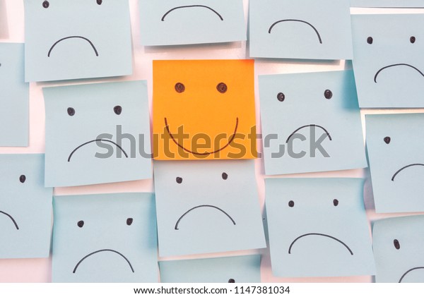 Positive Attitude and Happy\
Concept. Hand Drawn A Smile Face And Sad Emotion on Sticky Note\
Background.