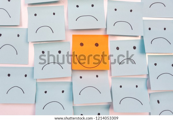 Positive Attitude and Happy\
Concept. Hand Drawn A Smile Face And Sad Emotion on Sticky Note\
Background.