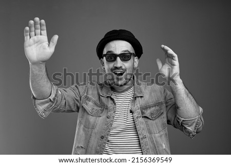 Positive attractive man in denim jacket being excited while waving his hands and keeping his mouth open