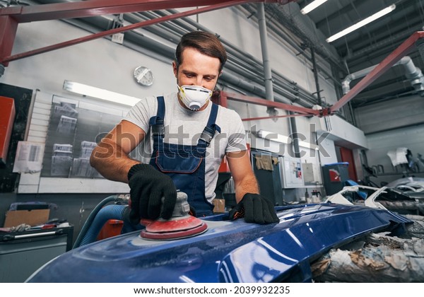 Positive automotive technician grinding automobile\
body part