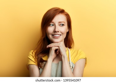 positive awesome young woman in apron falls in love. happy young woman with hand on her chin looking aside . close up photo.