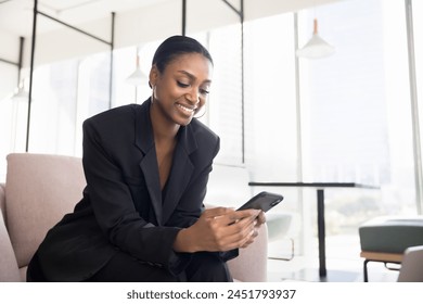 Positive beautiful Black business professional lady using application on cellphone for job communication, typing message on work chat, smiling, holding smartphone - Powered by Shutterstock